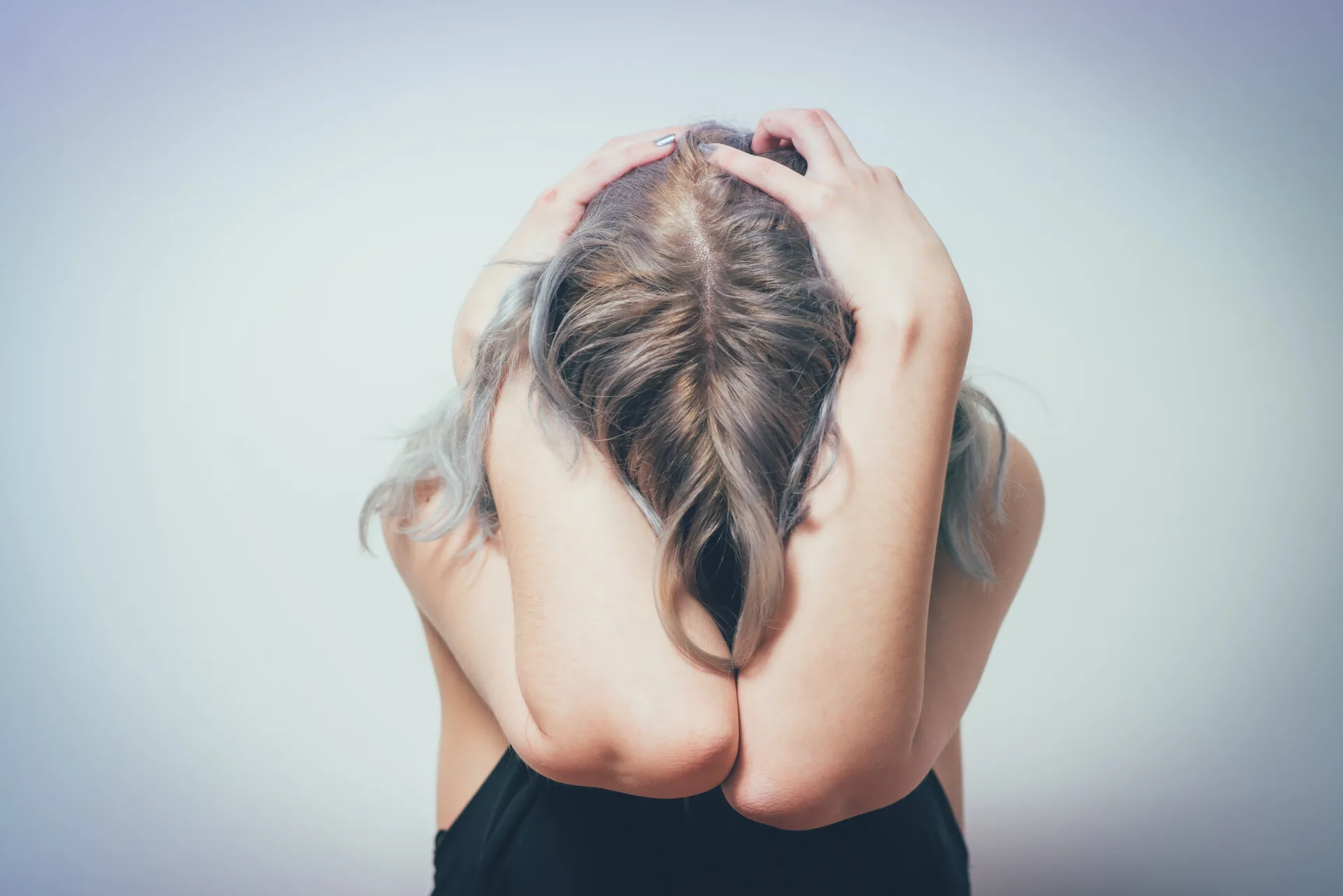 Kvinde sidder og gemmer hovedet i armene