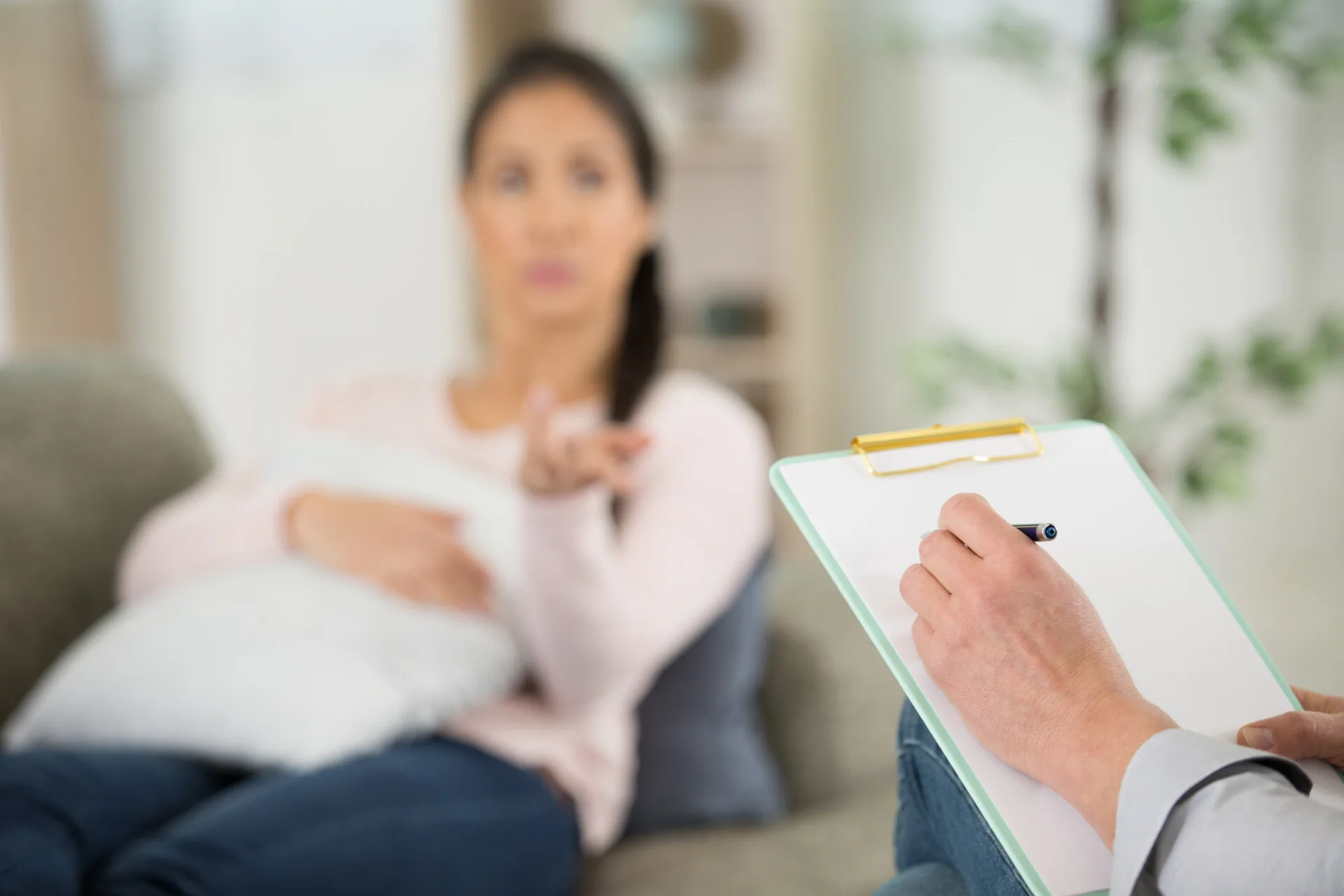 Kvinde sidder med pude i favnen, mens hun forklare noget