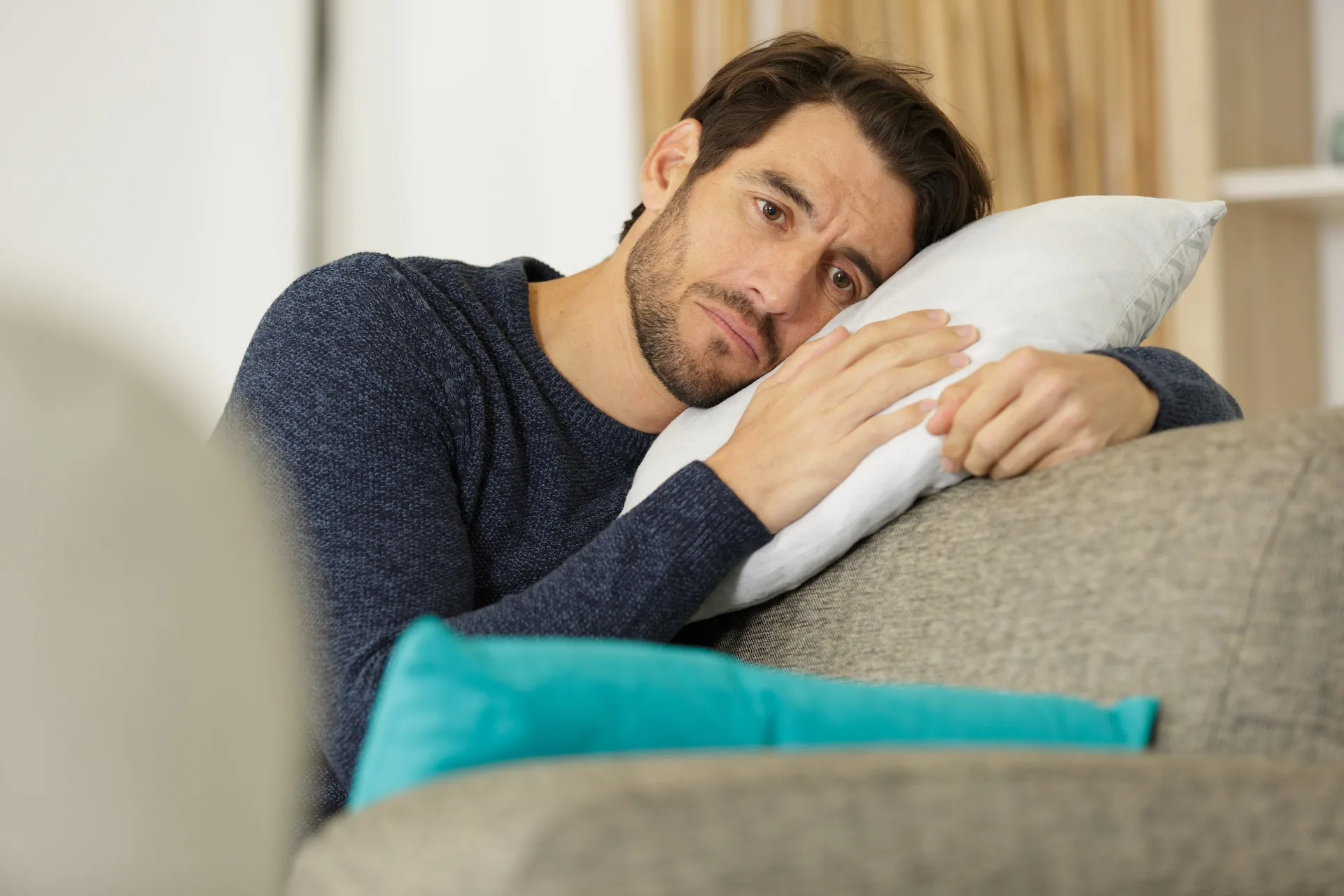 Mand ser trist ud og hviler hovedet mod en pude