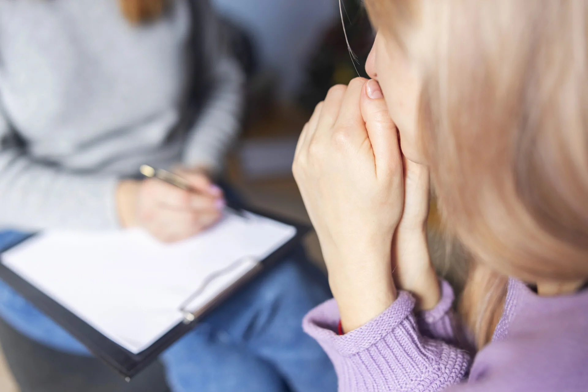 Kvinde sidder med hænderne oppe for munden