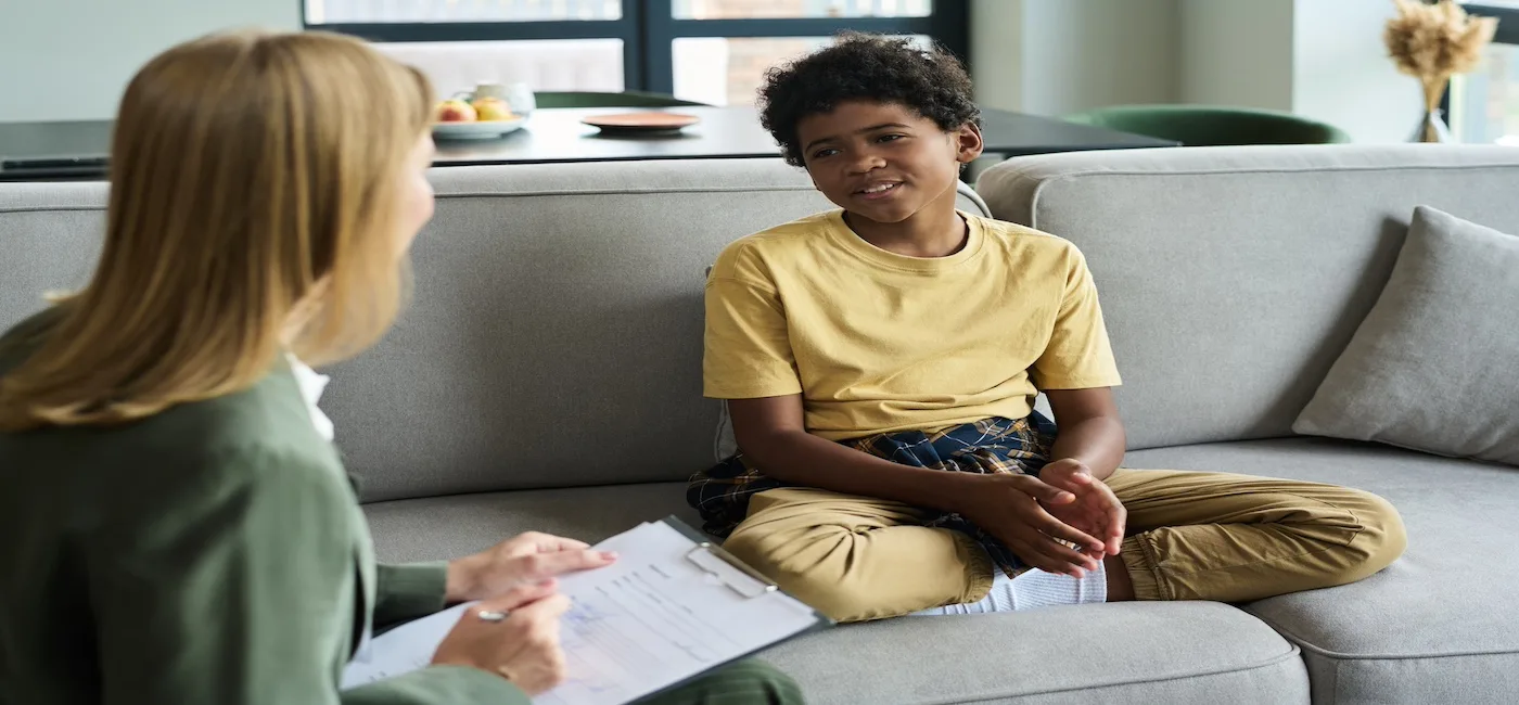 Dreng sidder i sofa og snakker med en kvinde