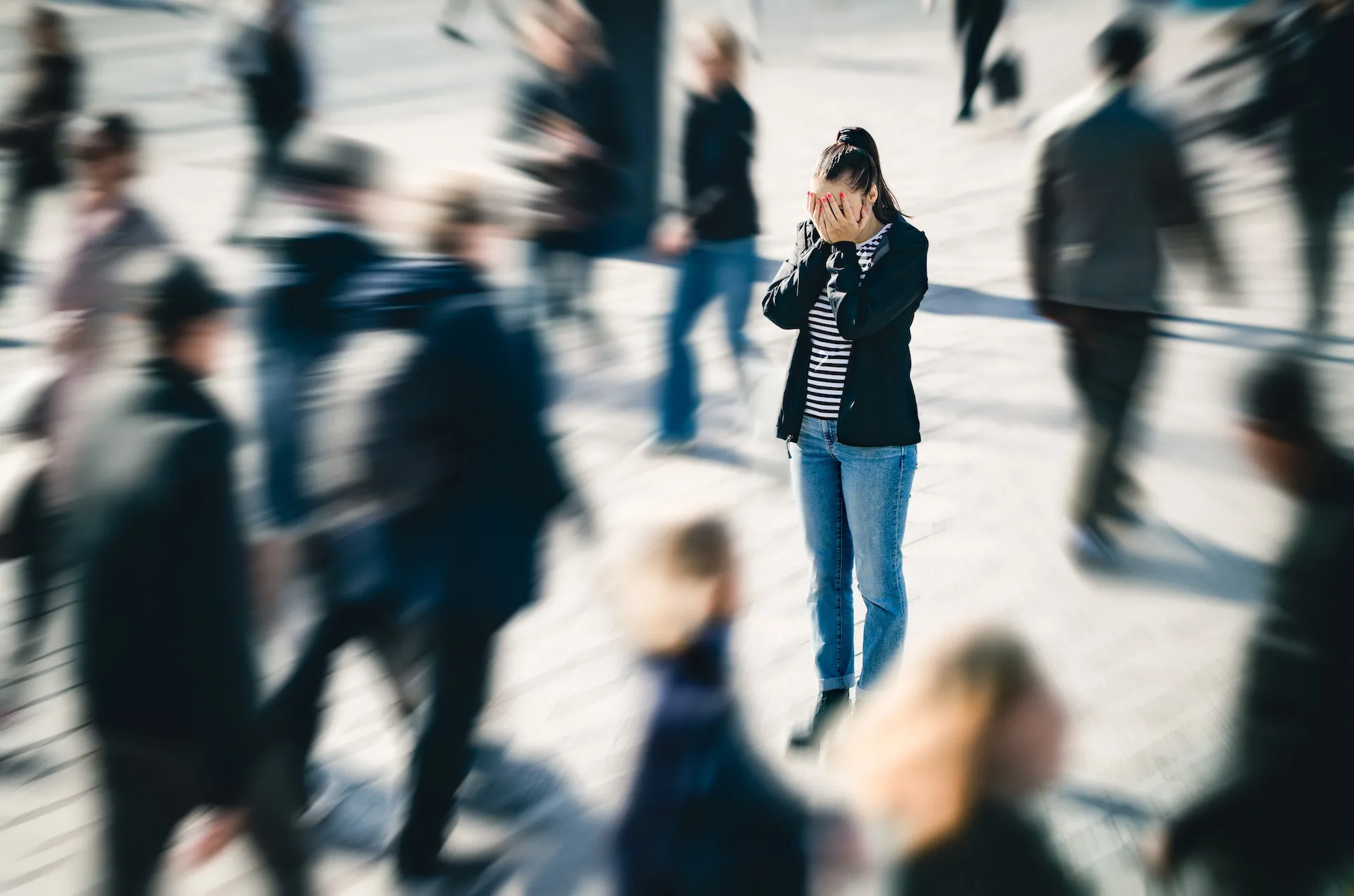 Kvinde står med hovedet i hænderne blandt andre mennesker