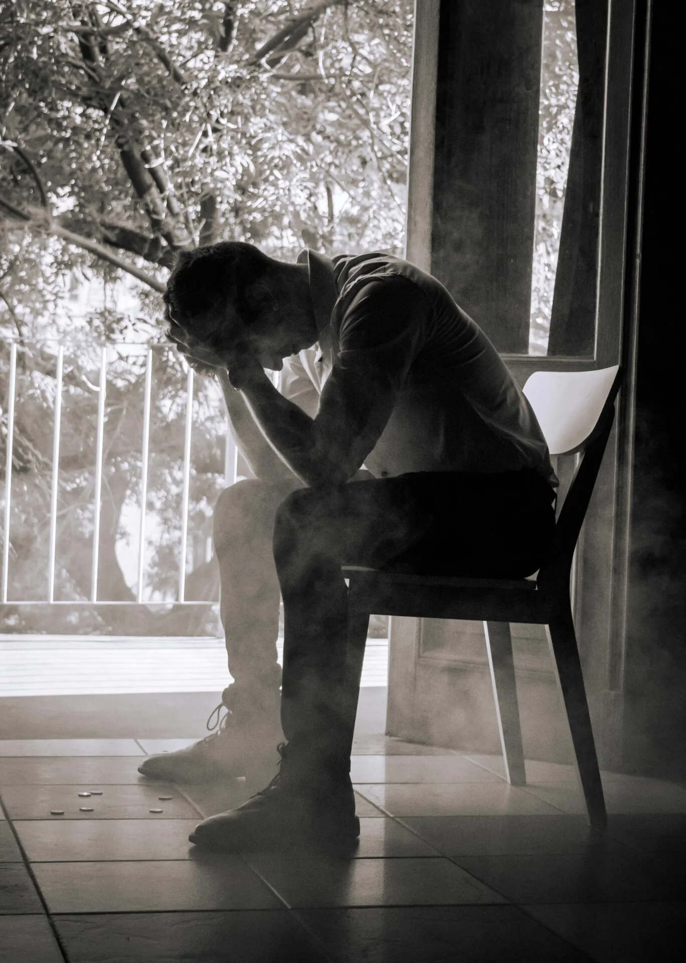 Mand sidder på stol med hovedet i hænderne